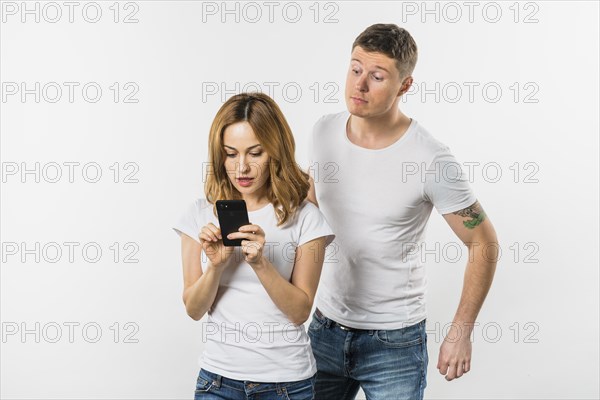 Young man trying spy her girlfriend s mobile phone isolated white background