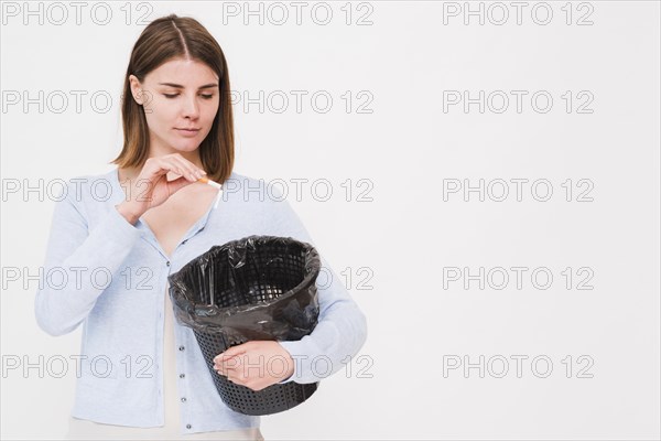 Young woman holding dustbin throwing cigarette