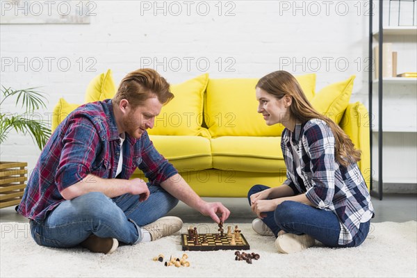 Young woman looking man playing chess game living room