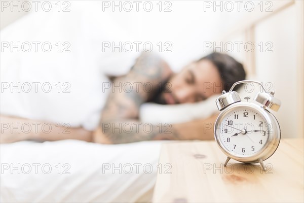 Alarm clock wooden desk with man sleeping background