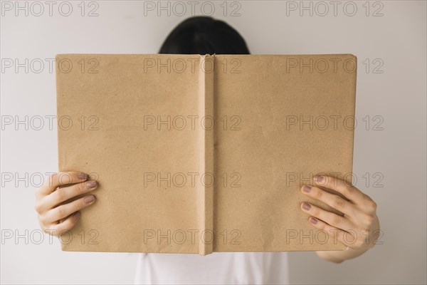 Anonymous woman showing book cover camera
