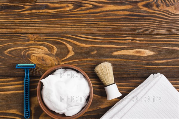 Blue razor foam shaving brush white folded napkin against wooden surface