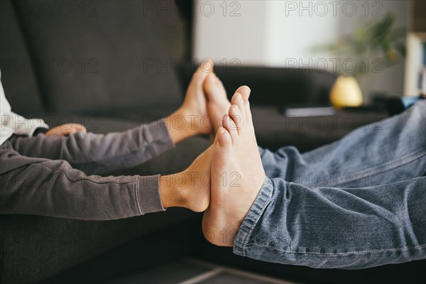 Child bare feet touching father feet