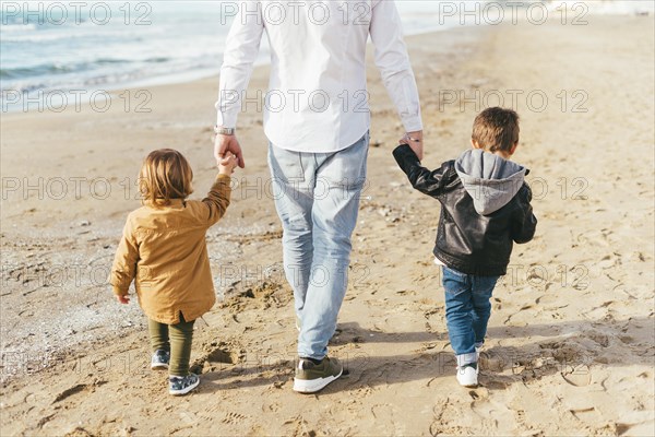 Children walking beach with dad