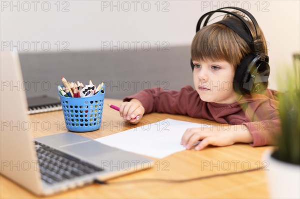 Child wearing headphones attending online school