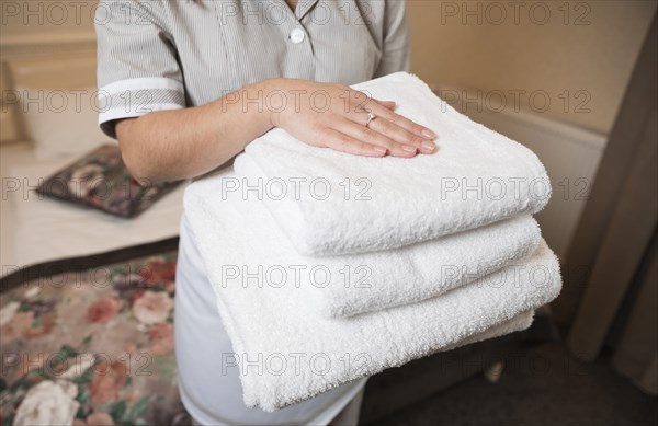 Close up female chambermaid holding clean soft folded towel hand