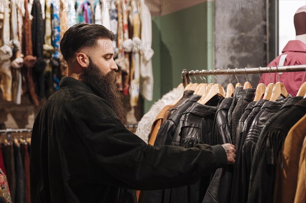 Close up man looking leather jacket rail clothing shop