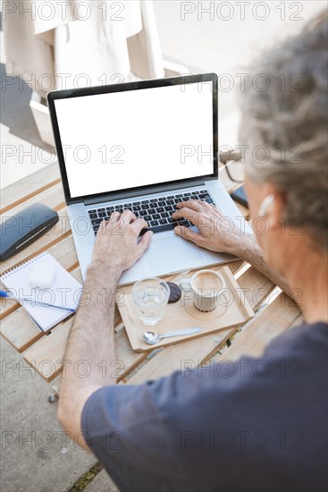 Close up man typing laptop with coffee water glass wooden table