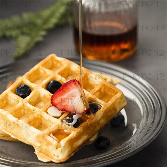 Close up view pouring maple syrup waffle