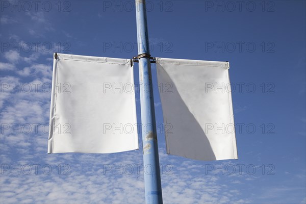 Close up white lamp post banner poster against blue sky