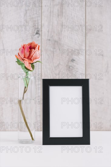 Colorful flower vase near blank picture frame table