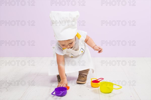 Cook child playing with toy dishes