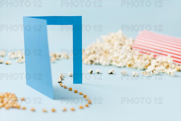 Corn seeds going through blue paper doorway turning into popcorn blue backdrop