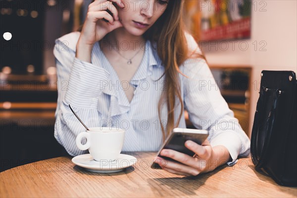 Crop woman using smartphone cafe table