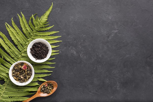 Dried herb tea white ceramic bowl with fern leaves black background