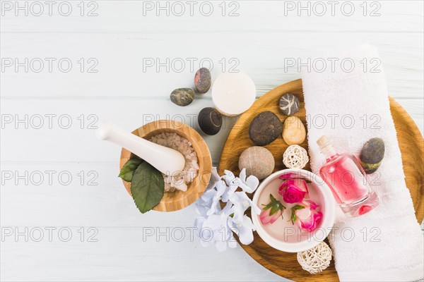 Elevated view spa stones salt towel flowers oil white background