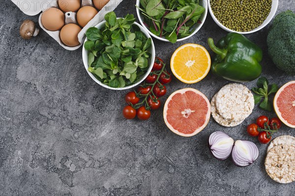 Elevated view vegetables eggs citrus fruit puffed rice cake gray concrete backdrop