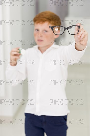 Freckle boy holding eyeglasses contact lenses container