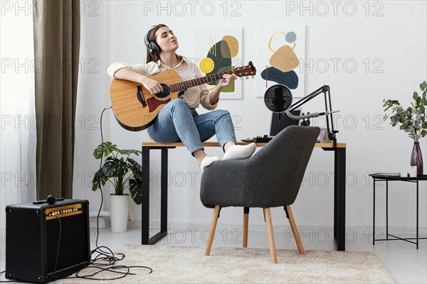 Front view female musician home playing acoustic guitar singing