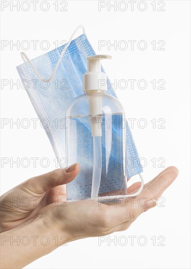 Front view hands holding hand sanitizer bottle medical mask