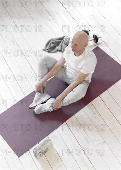 Full shot senior man sitting yoga mat