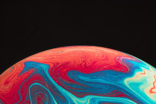 Gradient rippled multicolored soap bubble black background