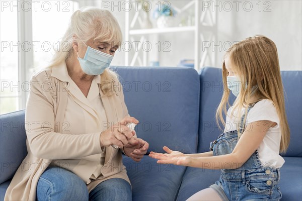 Grandma girl with mask using hand sanitizer