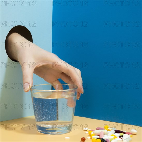 Hand grabbing glass water with pills it