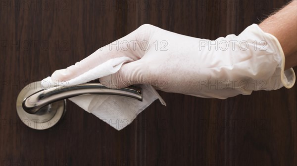 Hand with glove disinfecting door handle