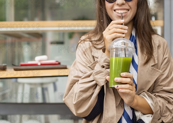 Happy woman drinking green smoothie