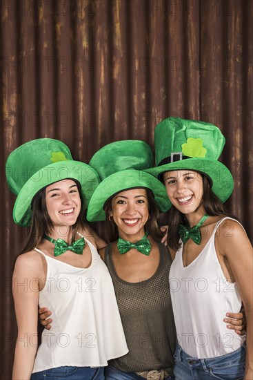 Happy young women saint patricks hats hugging near wall