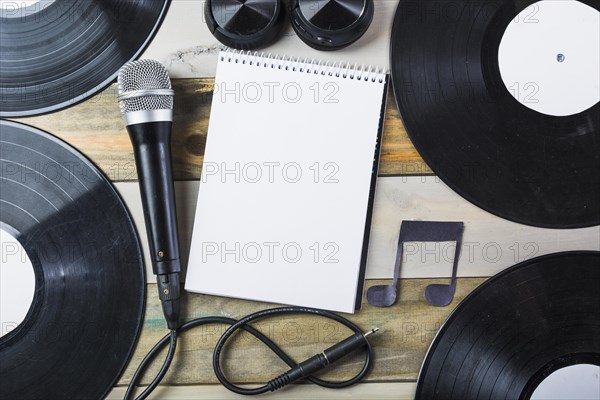 Headphone microphone vinyl record blank spiral notepad with musical note wooden table