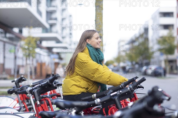 Young woman with bike at a bike station renting a bike in the city