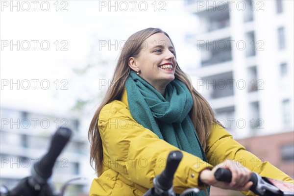 Young woman with bike at a bike station renting a bike in the city