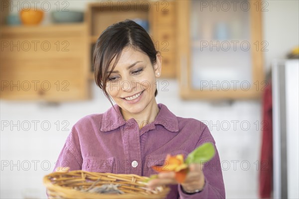 Woman in the kitchen disposes of organic waste in basket Environmental protection