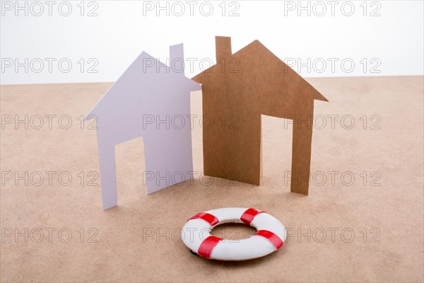 Little model life preserver and paper houses on a brown background