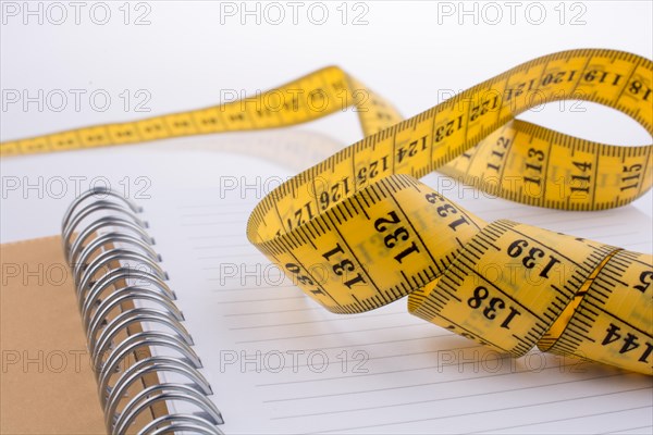Measuring tape near a notebook on a white background