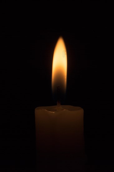 Burning white candle on a black background