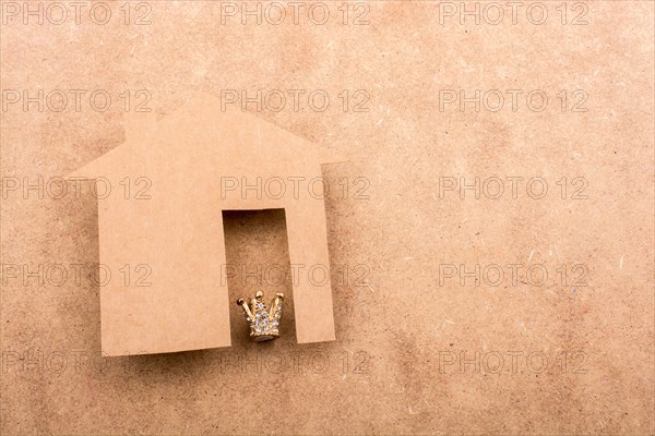 Litle model crown and paper house on a brown background