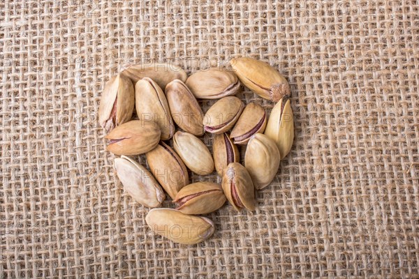 Pistachios form a heart shape on canvas background