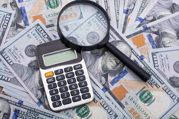 Magnifying glass is held over the banknote bundle of US dollar