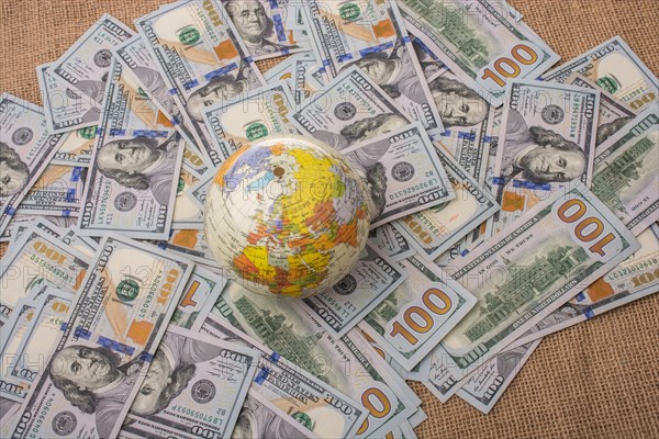 Model globe is placed on spread US dollar banknotes