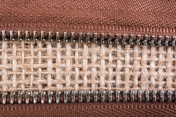 Parts of the brown color zipper on linen canvas background