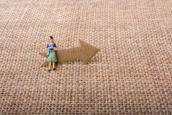 Figurine woman led by an arrow on canvas background