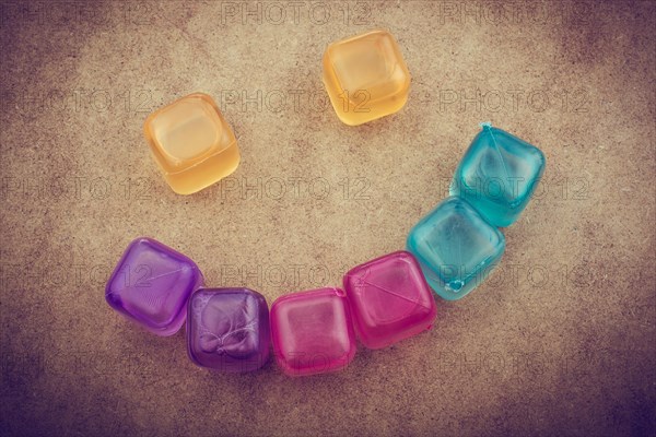 Fake colorful ice cubes on a brown background