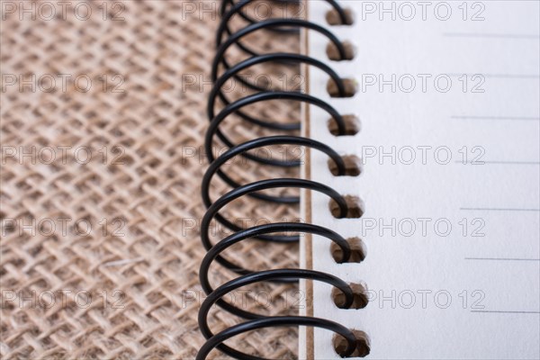 Brown color spiral notebook placed on a canvas background