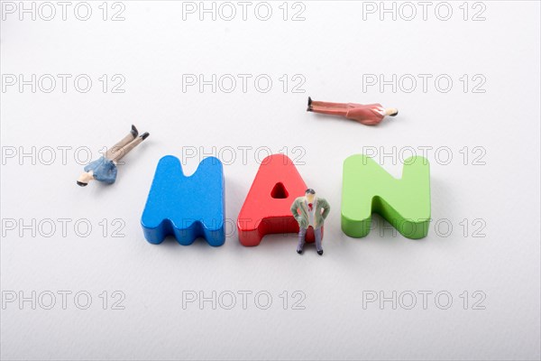 Tiny figurine of men beside colorful wooden letters say MAN