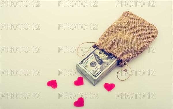 Red hearts and banknote bundle of US dollarin a sack