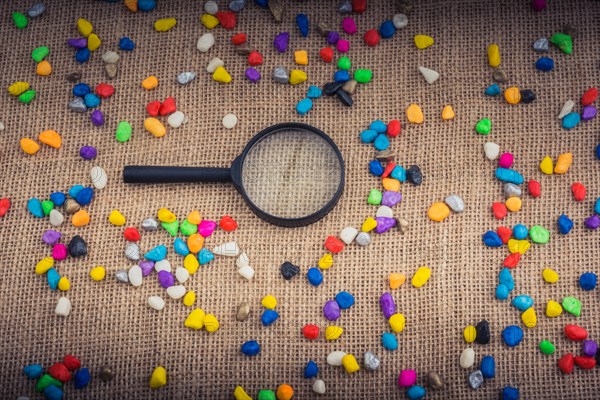 Magnifying glass amid Colorful pebbles