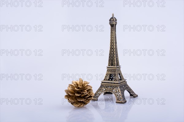 Little model Eiffel Tower and pine coneon a white background